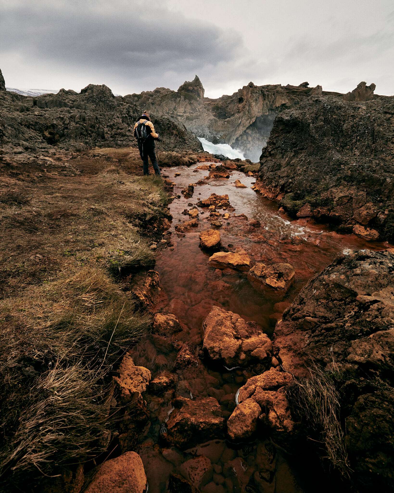 An orange colored lake in Iceland flows through a rocky and pointed landscape